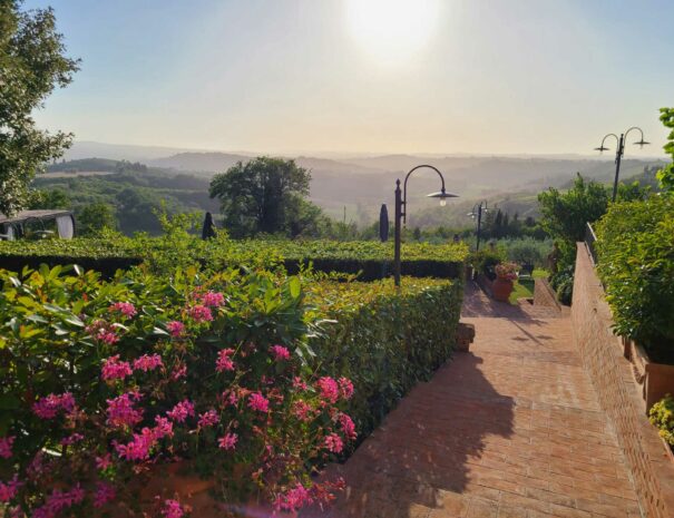 Villa Bellavista garden with fuchsia flowers; brick stairs; Chianti hills view in sun light - villa rentals by Timeless Tuscany tour operator